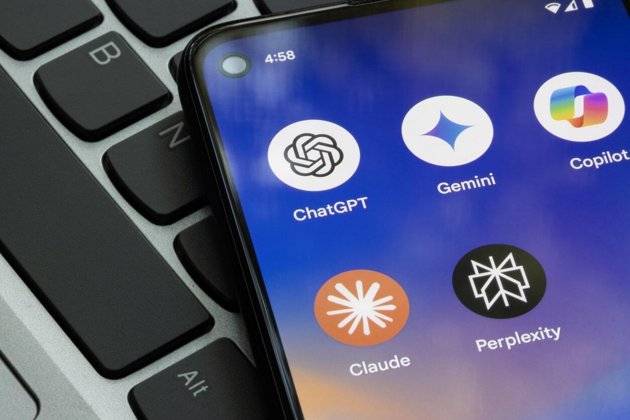 Image shows a keyboard with a phone on top, depicting AI apps such as ChatGPT, Claude, CoPilot