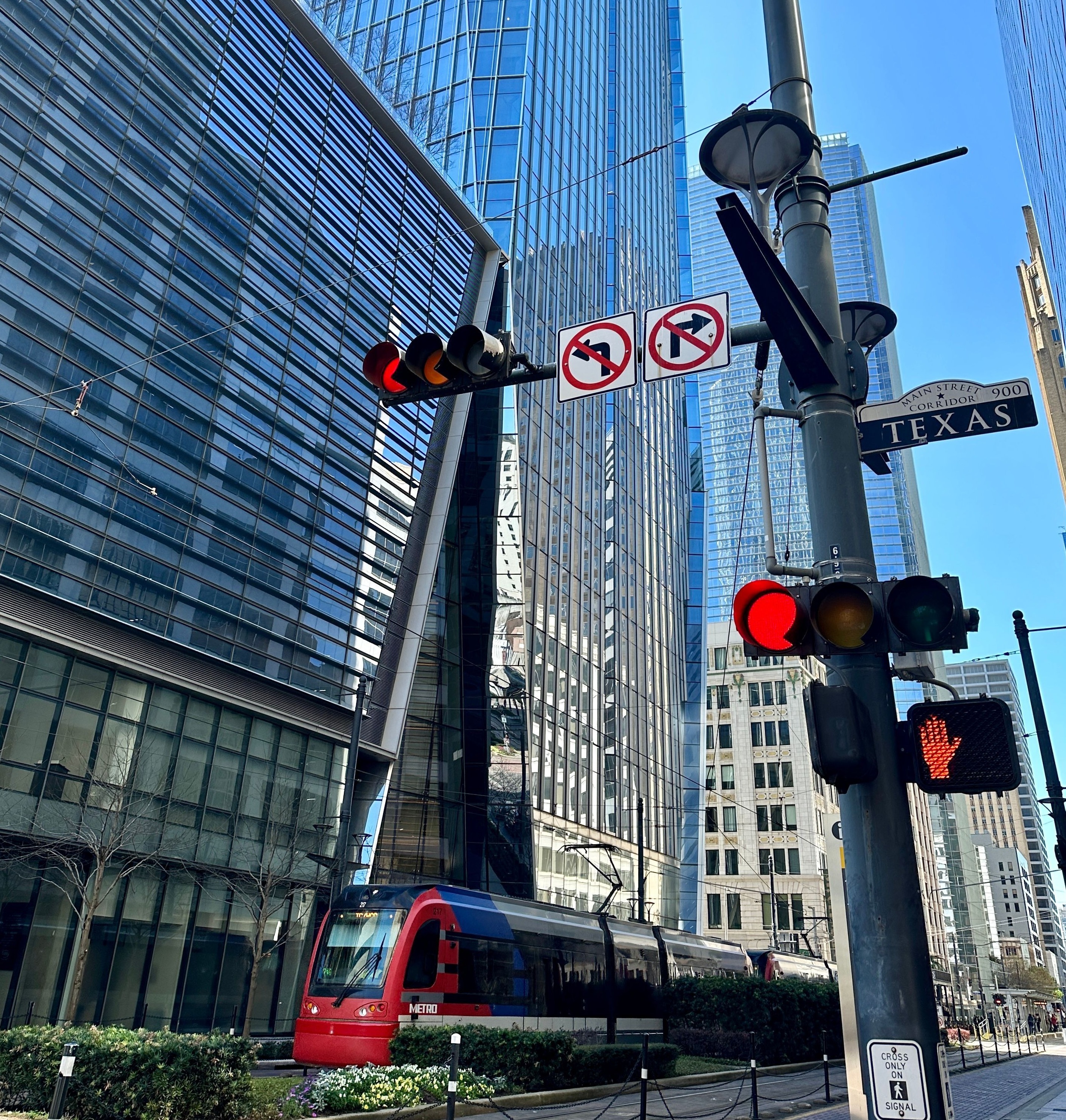 View of red tram passing skyscrapers on a sunny day in Houston, Texas