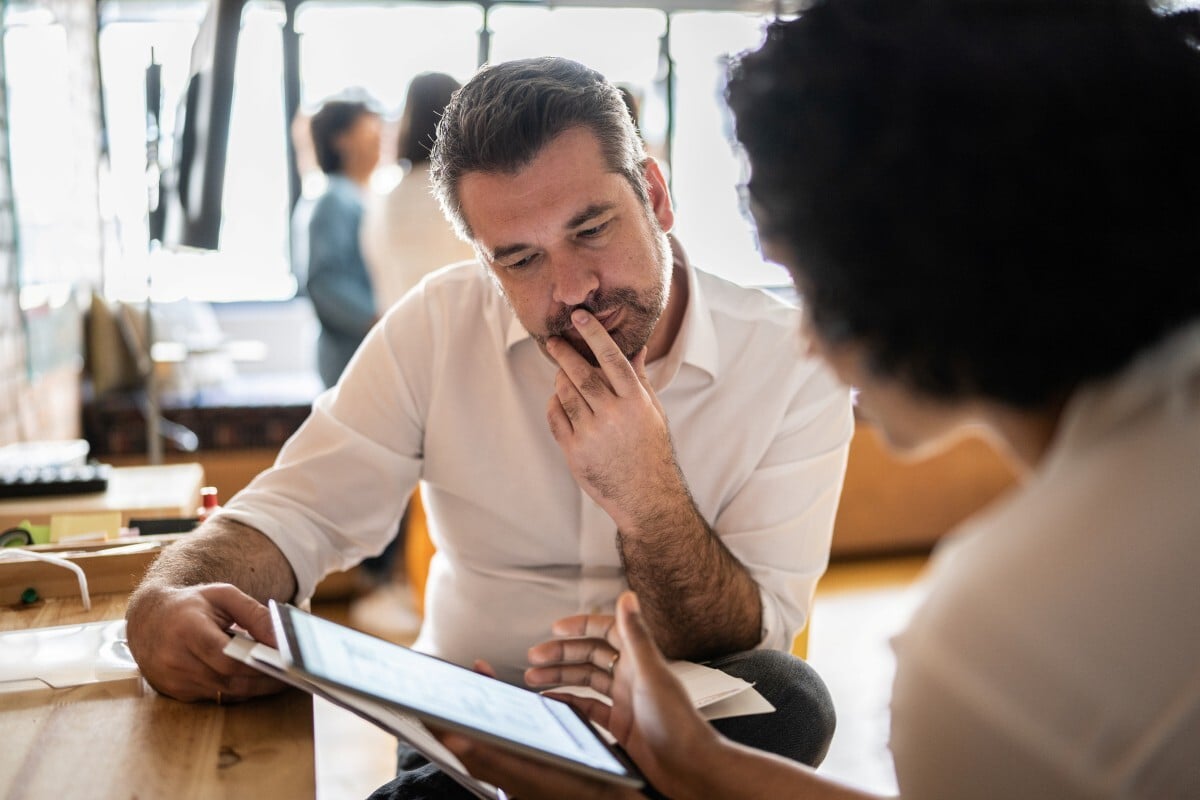 resized Mature man looking at a digital tablet that a colleague is showing at work stock photo